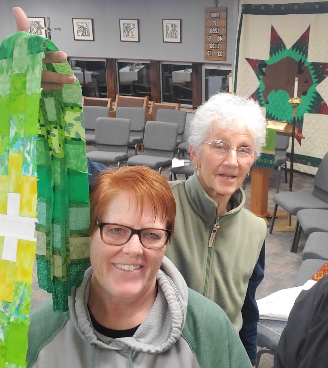 Two women holding patchwork cloth in church